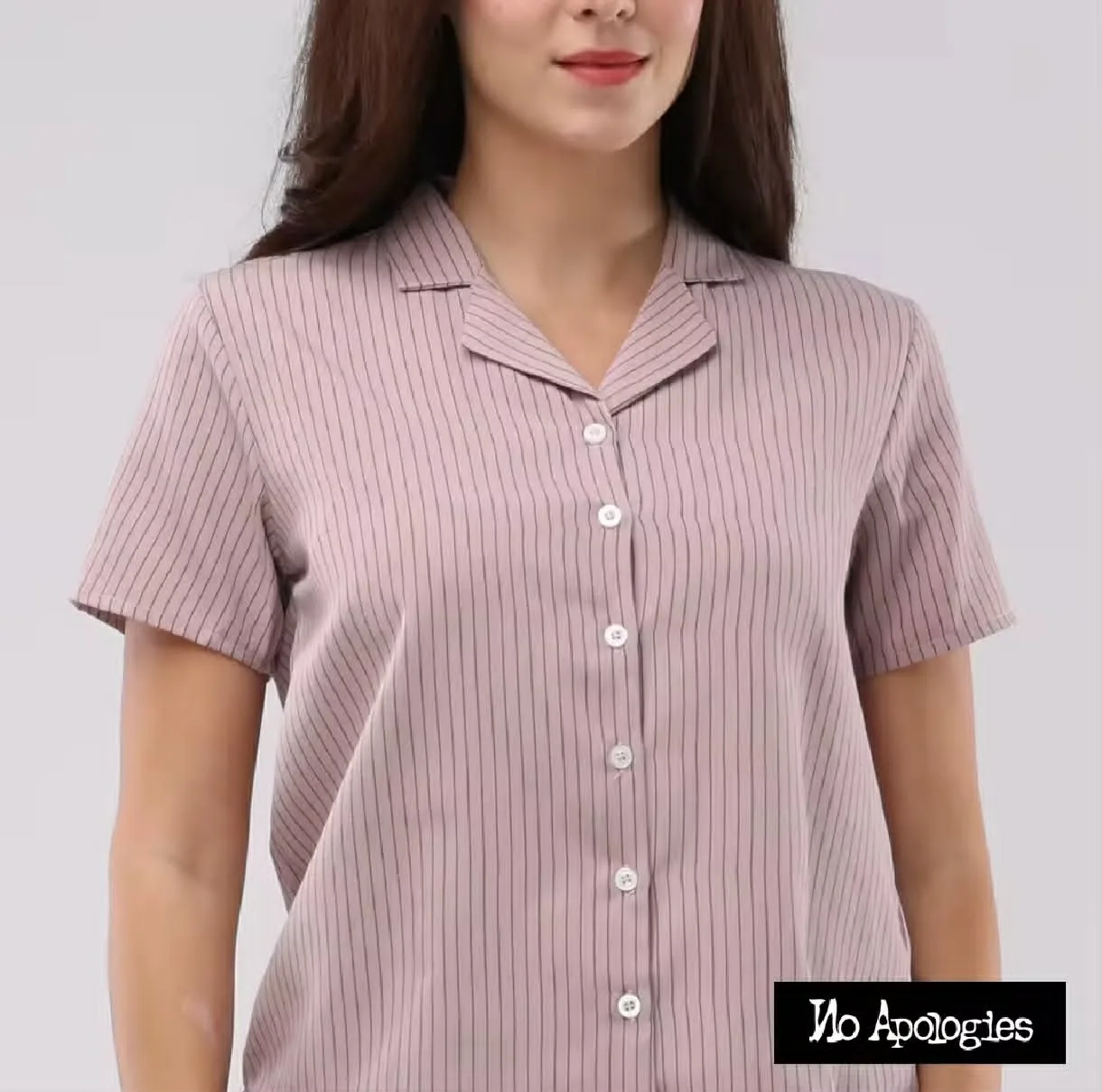 Design & Aesthetics This short-sleeved button-up shirt features a subtle, elegant dusty pink base with fine dark vertical pinstripes, offering a clean, professional yet relaxed look. The notch lapel/Cuban collar adds a touch of retro charm, making it stand out from standard casual shirts. The white buttons provide a sharp contrast down the front placket. Fit & Versatility The shirt offers a tailored, relaxed fit that lays flat across the shoulders and chest without feeling restrictive. Its versatile silhouette makes it easy to style for different settings: Casual: Pair with white linen trousers or light-wash jeans and sneakers. Workwear/Smart Casual: Tuck into high-waisted tailored trousers or a pencil skirt with loafers or heels. Fabric & Comfort The lightweight fabric feels smooth and breathable, ideal for warm weather or layering under a lightweight blazer. The structured collar maintains its shape well without stiffness. Verdict A chic, versatile addition to any wardrobe, seamlessly balancing understated professional style with effortless everyday casual wear.